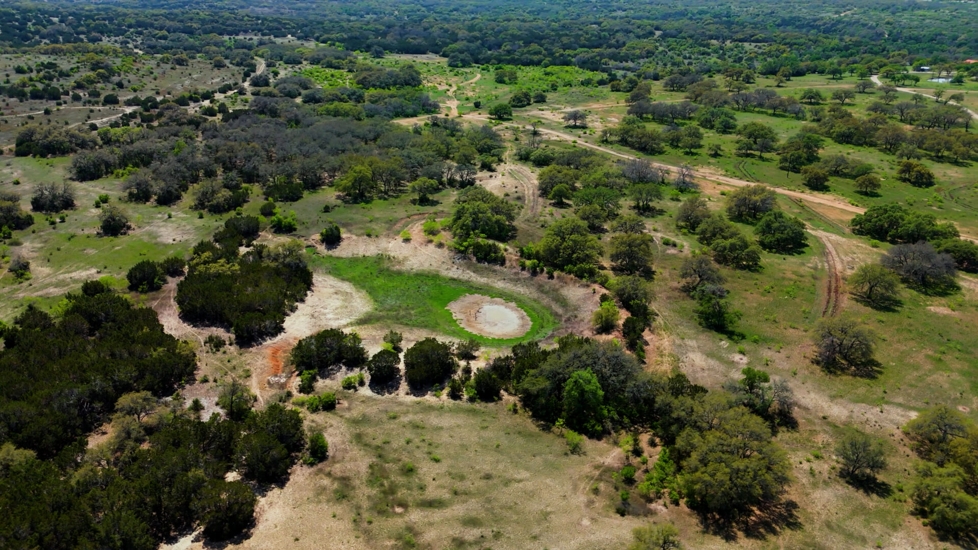 Aerial view of overgrazed pasture in Central Texas showing bare soil, erosion, and limited grass cover.