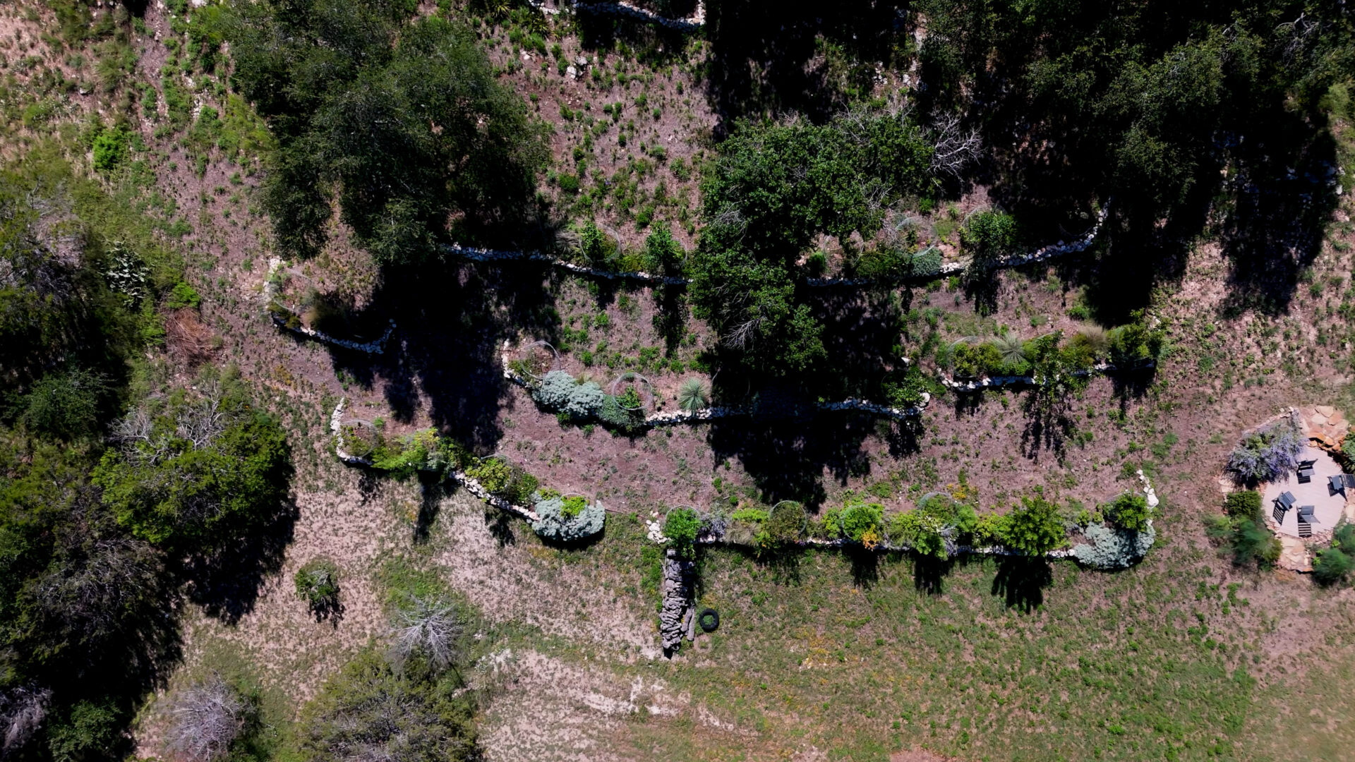 Aerial view of dry stack limestone terraces on a sloped Hill Country property in Central Texas designed for erosion control and water infiltration.