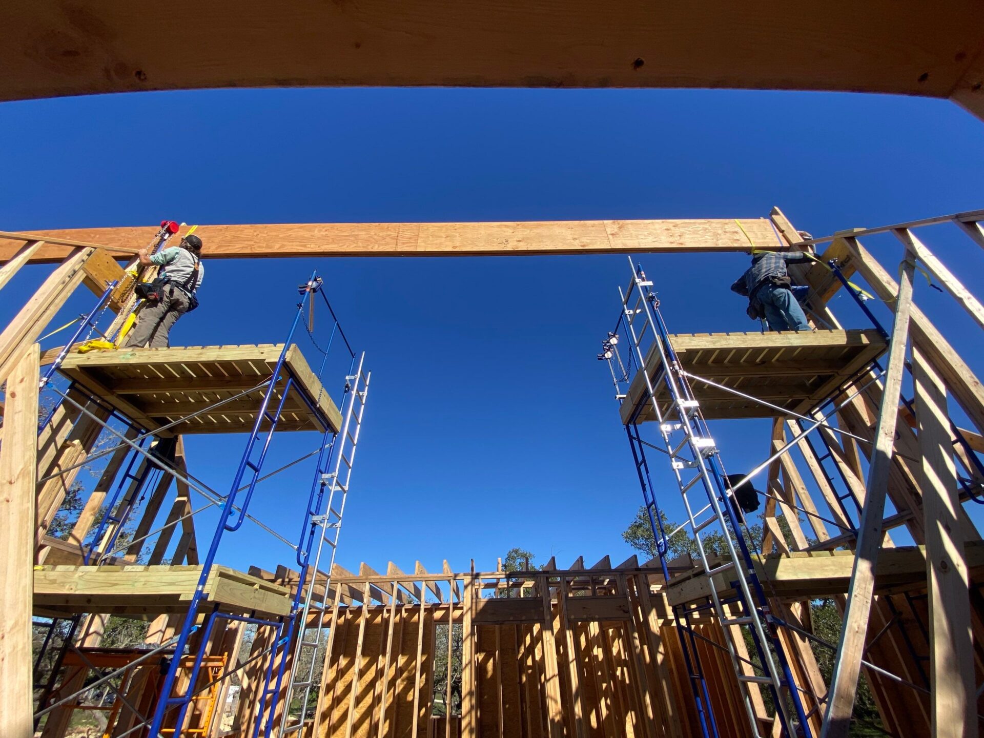 Crew lifting an LVL beam into place during framing of a Central Texas ecological home.