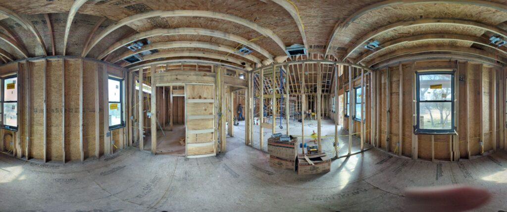 Panoramic view of two ecological homes under construction on a Central Texas property, sited among existing oaks.