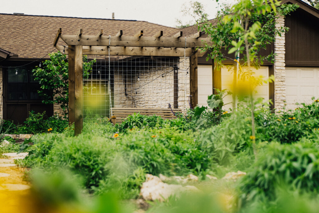 Custom wood pergola with a swing bench, surrounded by native plantings in a front yard